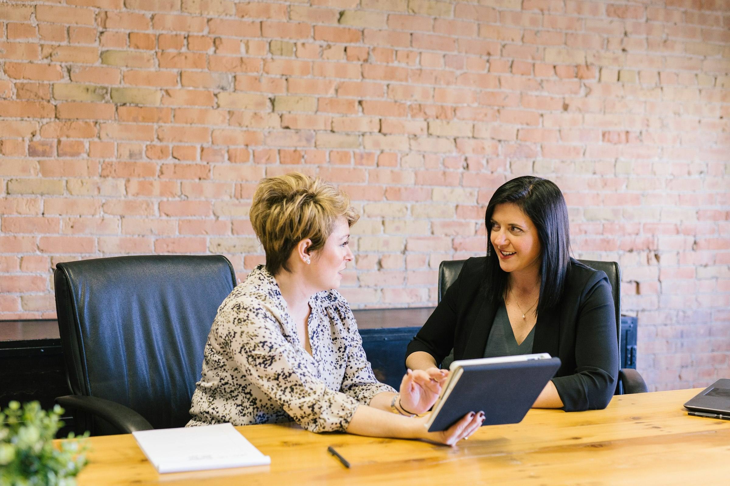 Two leaders at a conference table talking through a plan on a tablet
